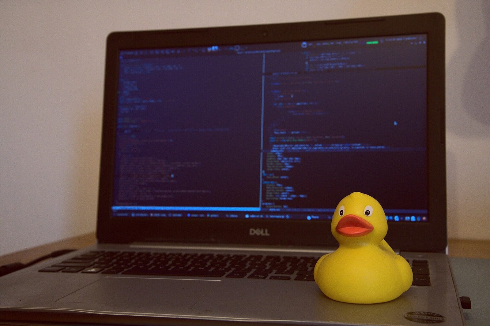 A rubber duck in front of a laptop full of code